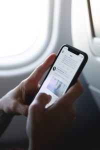 Online Presence - person on phone on airplane using Twitter