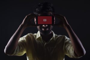 Video Marketing - Man holding phone over face with YouTube App