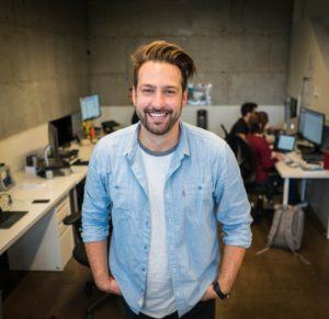 company culture - man smiling standing in community office space