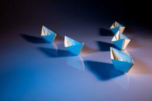 leadership - paper boats on white table